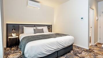 Une chambre à coucher bien rangée, avec un lit, une table de chevet et un appareil de climatisation.