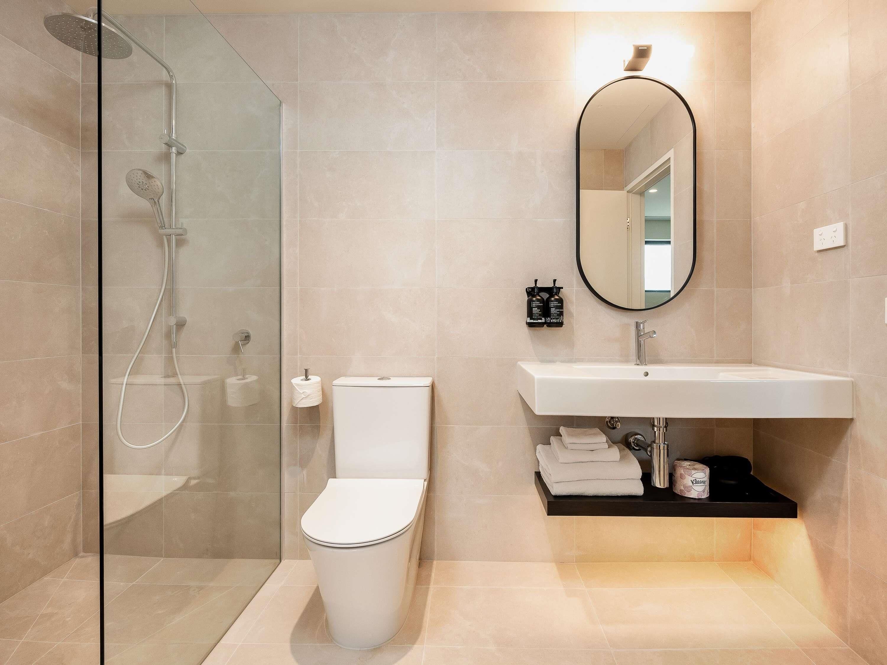 Un baño moderno con cabina de ducha de vidrio, inodoro, lavabo y espejo.