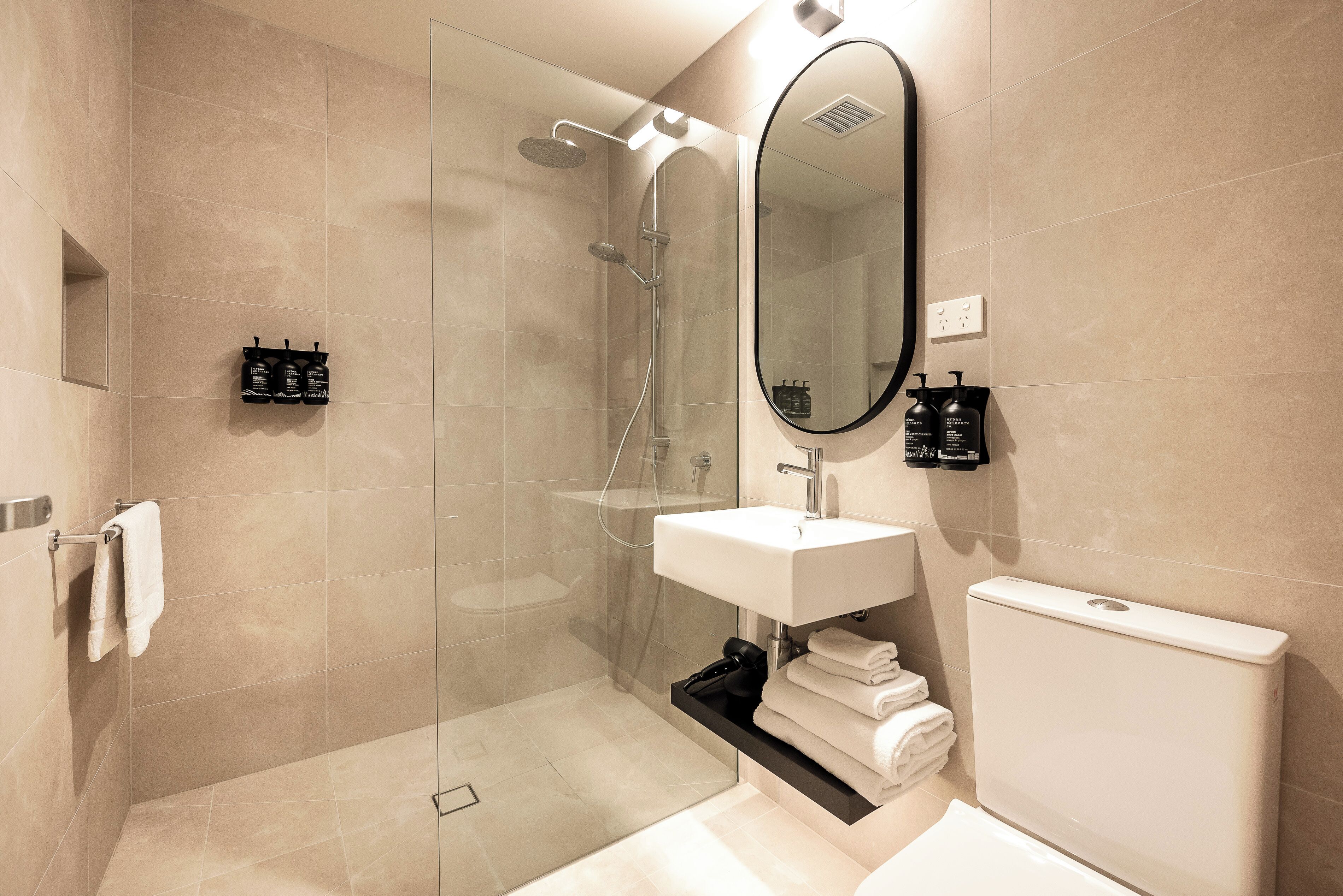 Une salle de bain moderne avec une douche à parois de verre, un lavabo blanc et des toilettes.