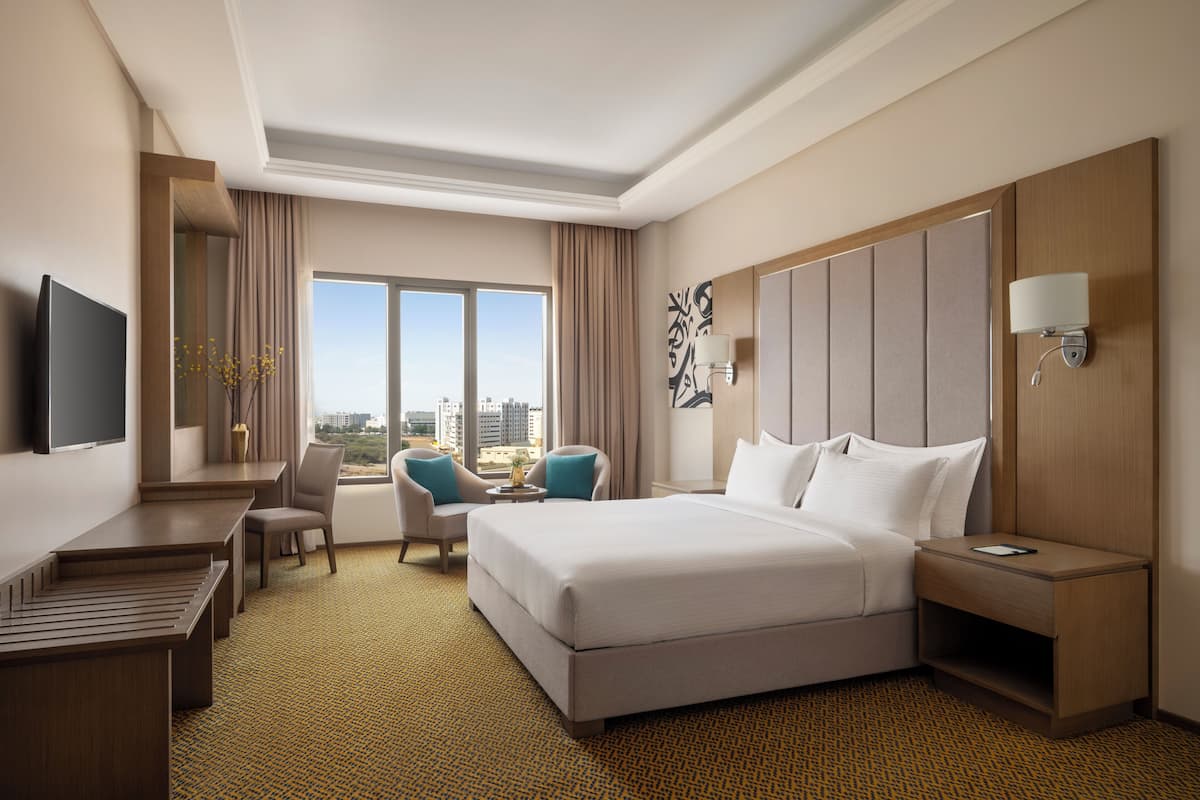 Une chambre d’hôtel avec un grand lit, un bureau, une chaise, une télévision et une vue sur la ville.