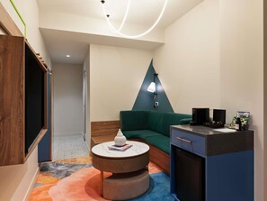 A modern room with a green sofa, a round coffee table, a small cabinet, and a unique wall-mounted lamp. - The Clarence Hotel Sydney by Accor (Sydney)