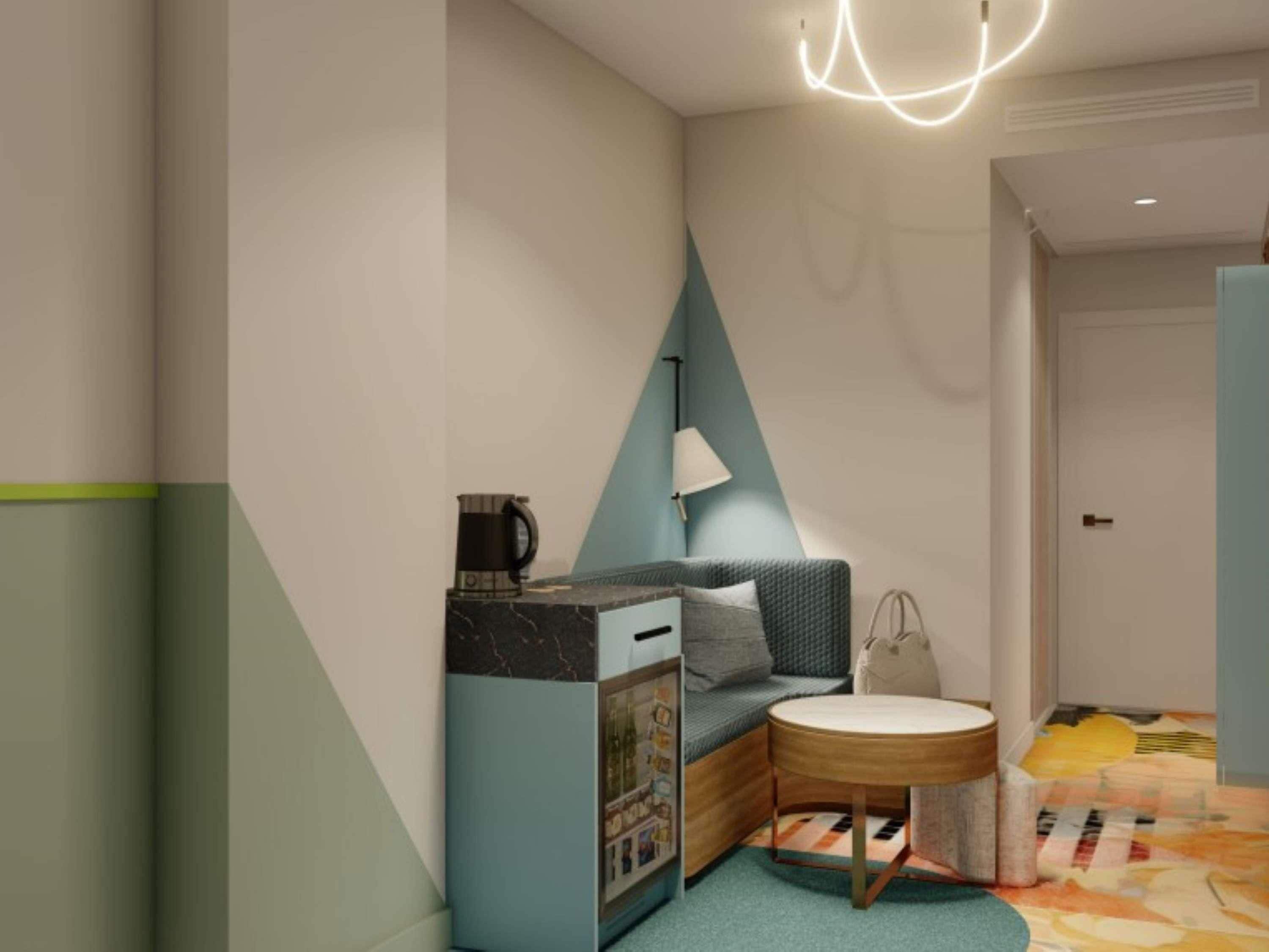 A modern hotel room with a sofa, a small table, a lamp, and a coffee machine.