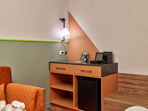 A compact room with a desk, a small refrigerator, a lamp, and a bed with an orange headboard. - The Clarence Hotel Sydney by Accor (Sydney)