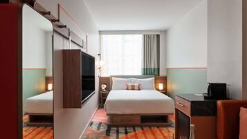 Habitación de hotel con cama, mesitas de noche, televisor, escritorio, silla, sofá y minibar.