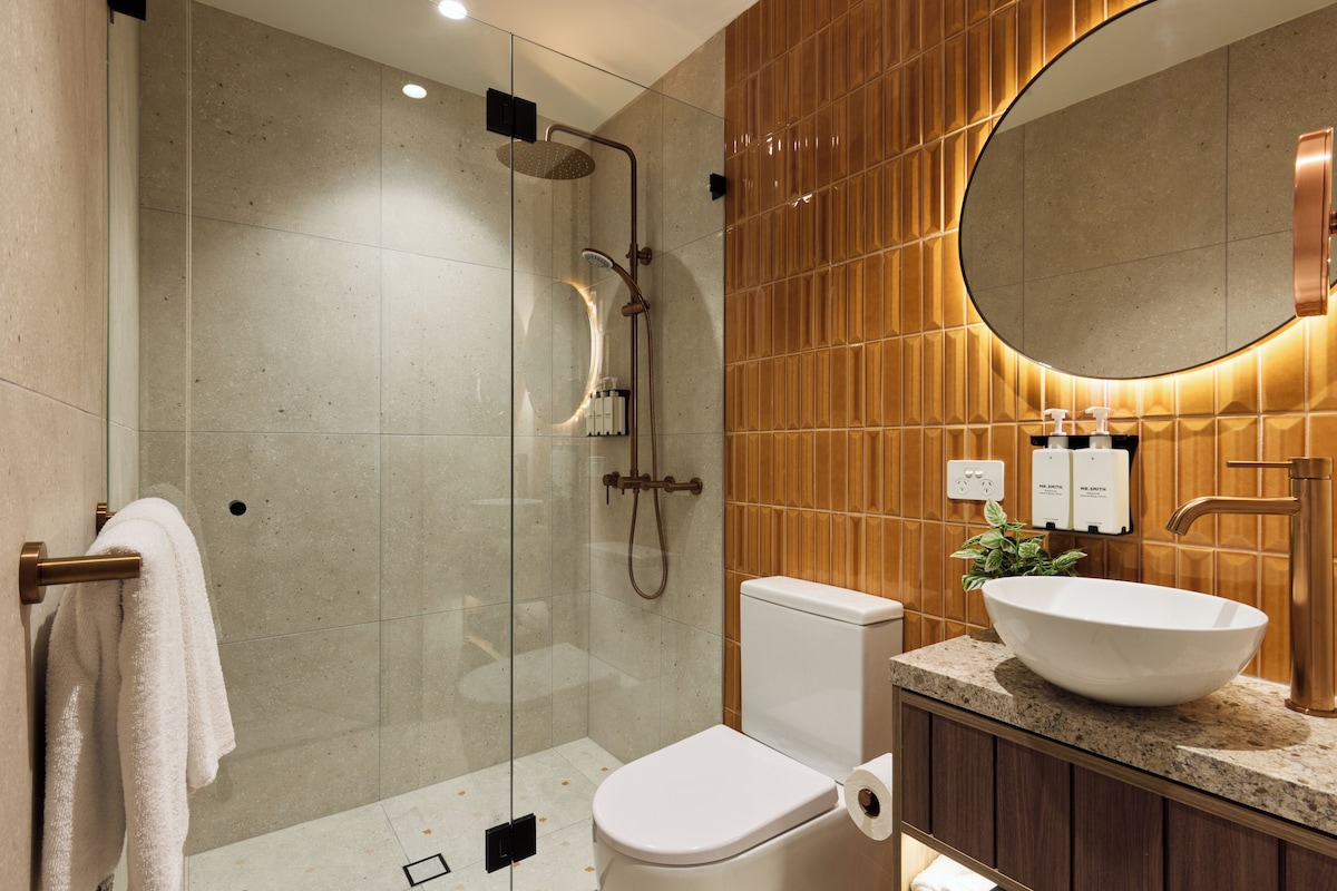 Une salle de bain moderne avec une douche à parois de verre, des toilettes blanches et un grand lavabo ovale.