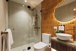 Une salle de bain moderne avec une douche à parois de verre, des toilettes blanches et un grand lavabo ovale.