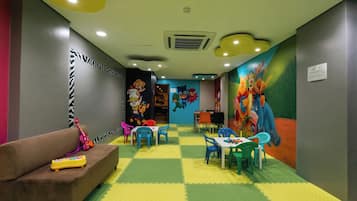Children can play and relax in this vibrant play area with a checkered floor, colorful murals, and comfortable seating.