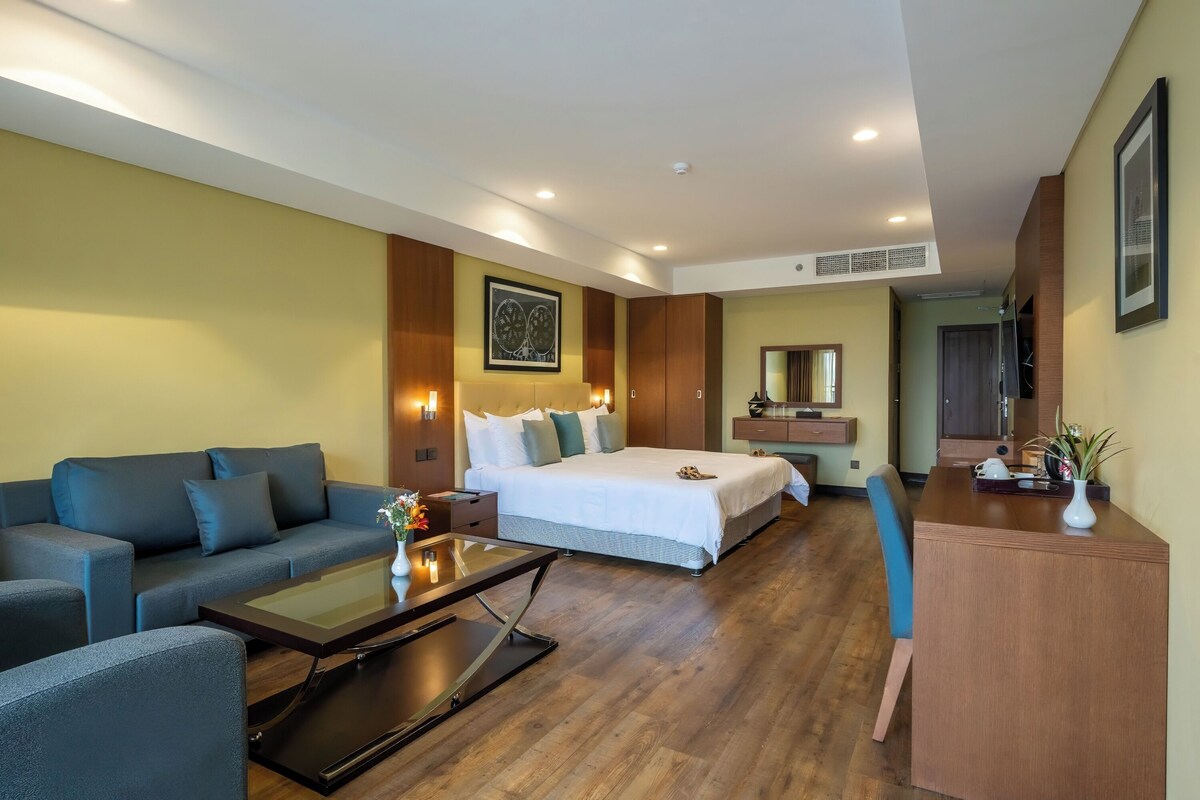 Une chambre d’hôtel moderne dotée d’un grand lit, d’un canapé, d’un bureau et d’un coin repas.