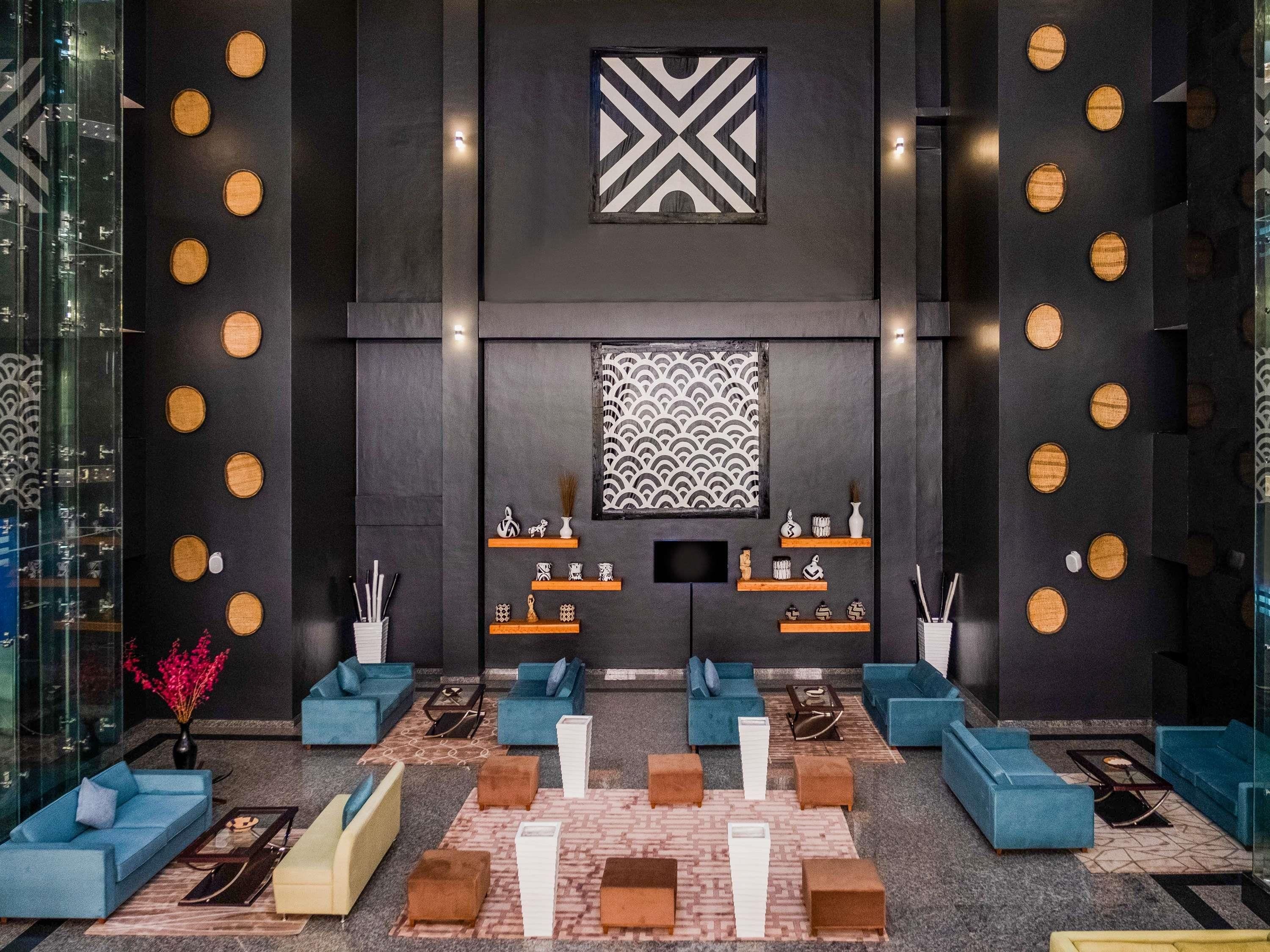 A modern lobby with blue sofas, a patterned wall, and a geometric design on the ceiling.