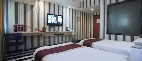 A hotel room with two beds, a TV, a desk, and a striped wall.
