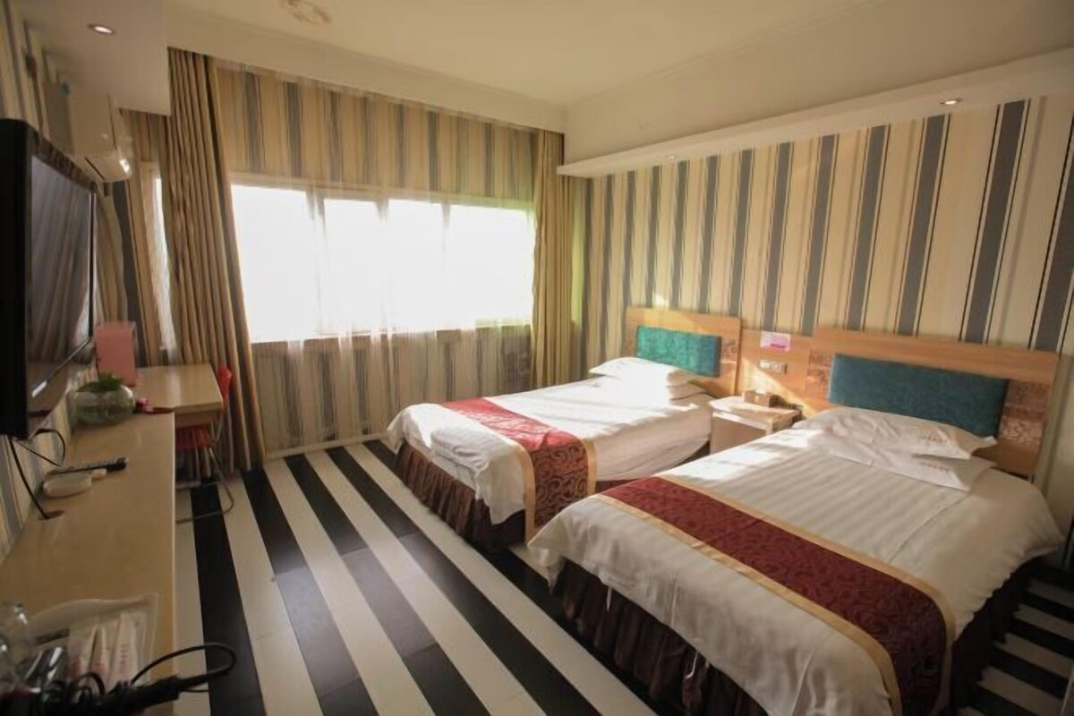A hotel room with two beds, a desk, and a TV.