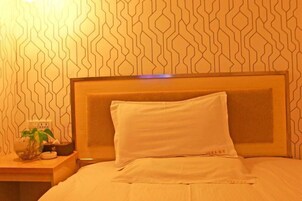 Una cama bien hecha con cabecera de madera y una almohada blanca.