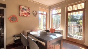 Comedor con mesa, sillas y vistas al exterior a través de amplias ventanas.