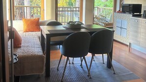 Comedor con una mesa, sillas y vistas al exterior a través de amplios ventanales.
