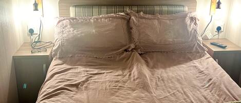 A bed with a headboard, two bedside tables with lamps, and a blanket on the bed.