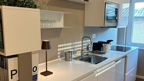 A modern kitchen with white cabinetry, a built-in island with a sink, and a microwave above the counter. - Luxurious apartment, close to the center (Roma)