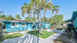 A residential area with two blue houses, a sidewalk, and palm trees. - Cozy studio in awesome Fort Lauderdale with WiFi and parking (Fort Lauderdale)