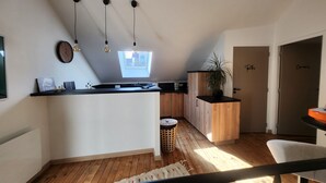 A modern kitchen with a wooden island, pendant lights, and a view of the city through a skylight. - Chambre Frida Kalho (Laval)
