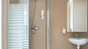 Un baño moderno con cabina de ducha de vidrio, un lavabo blanco y un espejo encima.