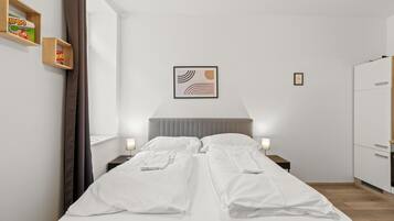 Una habitación de hotel con cama, mesitas de noche, un armario y una obra de arte enmarcada en la pared.