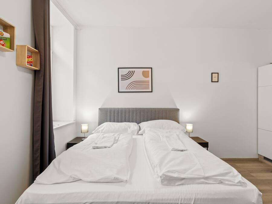 Una habitación de hotel con cama, mesitas de noche, un armario y una obra de arte enmarcada en la pared.