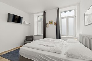 A modern hotel room with a large bed, a TV mounted on the wall, and a window with curtains. - Faraway Studios 43 (Vienna)