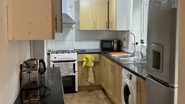 Una cocina compacta con estufa, microondas, lavabo y lavadora.