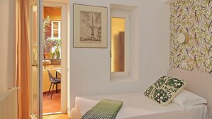 Una habitación con una cama, un ventanal, un cuadro enmarco y un papel tapiz decorado.