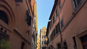 Una estrecha calle adoquinada bordeada por edificios históricos con puertas arqueadas y ventanas con contraventanas.
