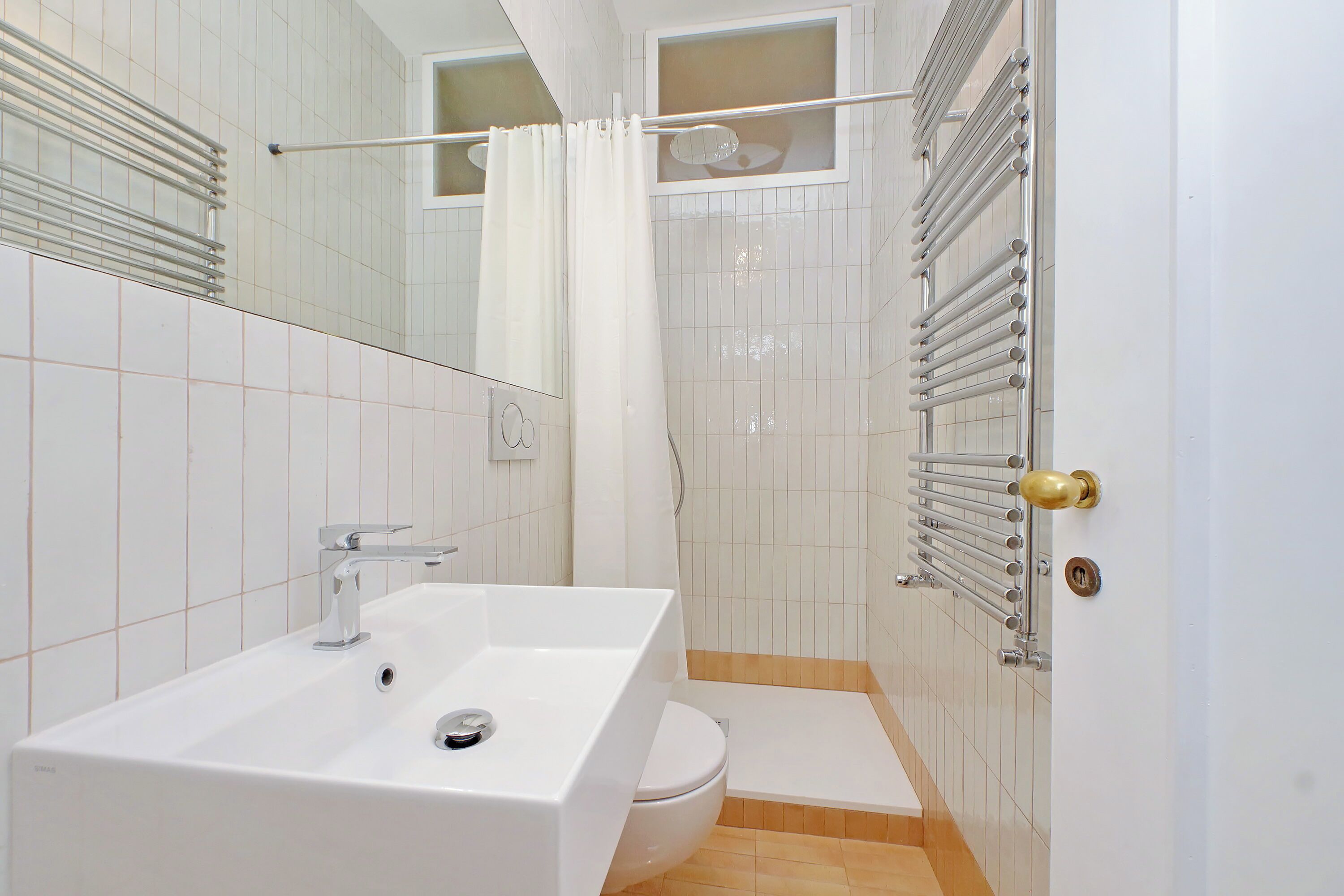 A modern bathroom with a white sink, toilet, and shower area.