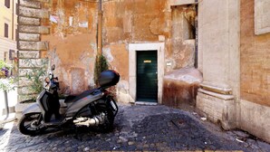 Una patineta estacionada frente a un edificio con una puerta verde y una escalera de piedra.