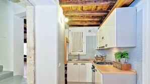 Cocina compacta con armarios blancos, encimera de madera y salpicadero de azulejos.