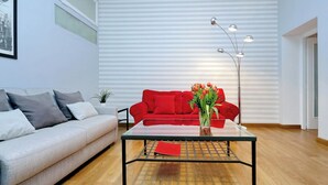 Un salon moderne avec un canapé rouge, une table basse en verre et un lampadaire.