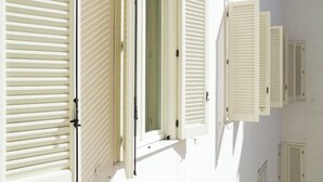 A building facade with multiple windows and shutters.