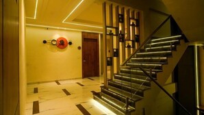 A modern staircase with a metal railing and a wooden door at the top. - Familia Hotel and Banquets (Lucknow)
