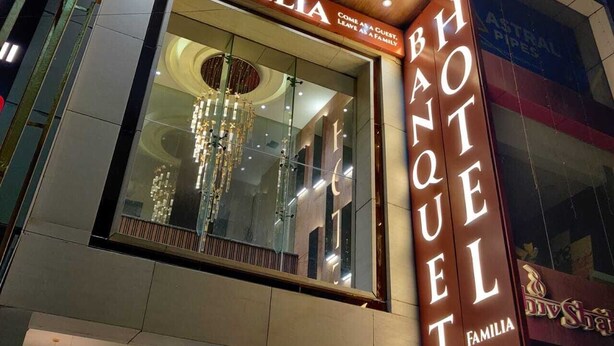 A hotel facade with a large illuminated sign reading "BANQUET FAMILIA" and a visible interior with a chandelier. - Familia Hotel and Banquets (Lucknow)