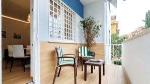 A balcony with two chairs and a table, a window with a view of the city, and a potted plant. - Cozy Domar - Two Bedroom Apartment, Sleeps 6 (Rome)