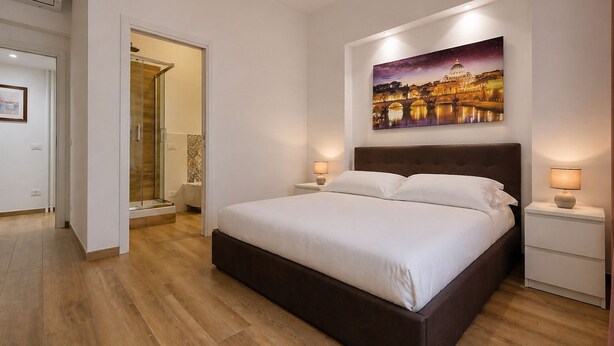 A bedroom with a large bed, two bedside tables, a nightstand, a painting on the wall, and a door leading to another room. - Cozy Domar - Two Bedroom Apartment, Sleeps 6 (Rome)