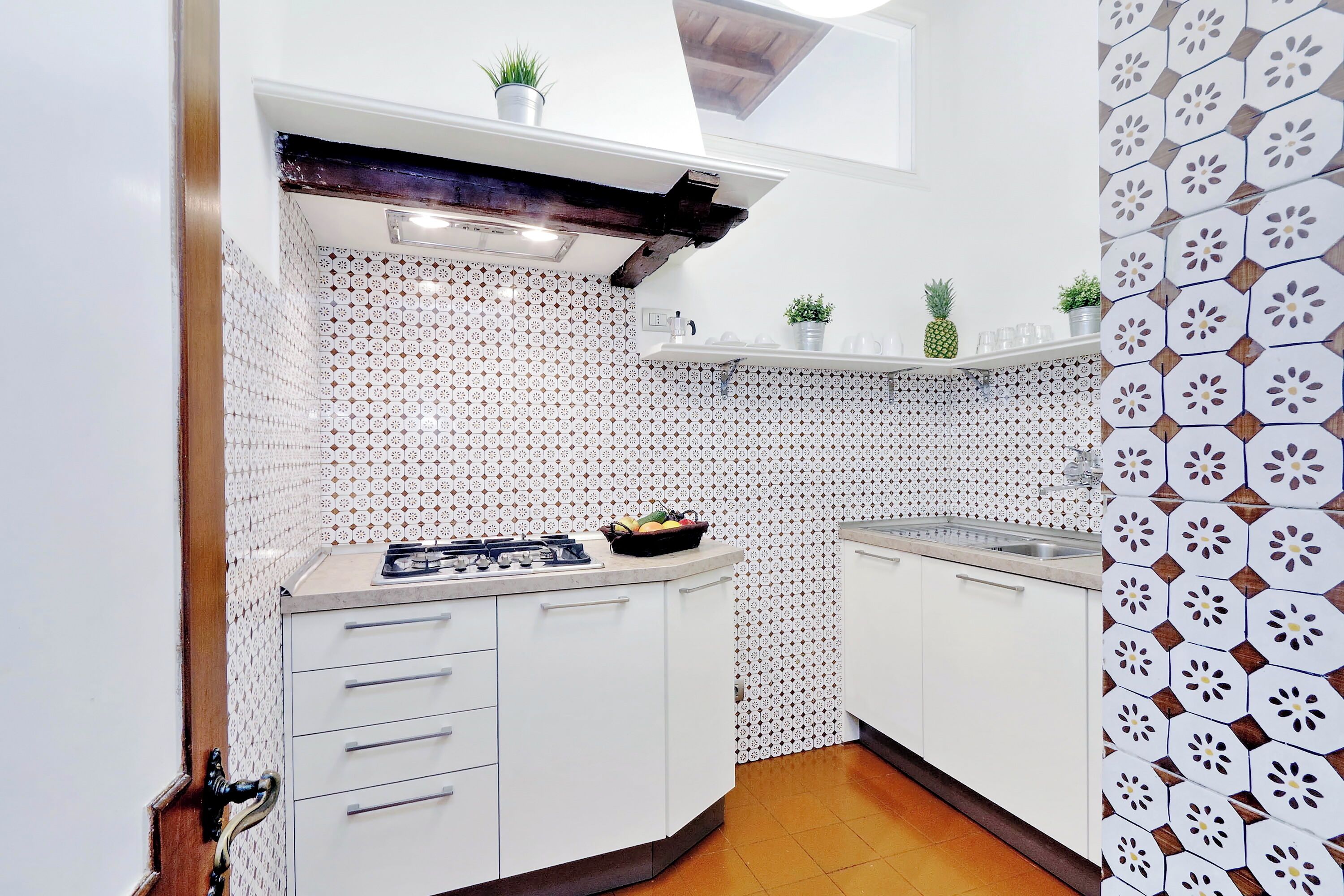 A kitchen with white cabinets, patterned backsplash, and a wooden ceiling.