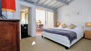Un dormitorio con una cama, una mesita de noche de madera, una lámpara y vistas al exterior.