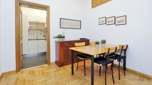 A dining area with a wooden table and chairs, a cabinet with decorative items, and framed pictures on the wall. - Cozy Oppio - One Bedroom Apartment, Sleeps 4 (Rome)