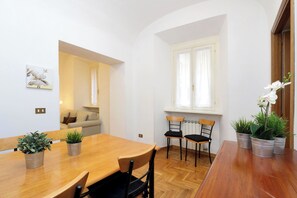 A dining area with a wooden table, four chairs, and potted plants.