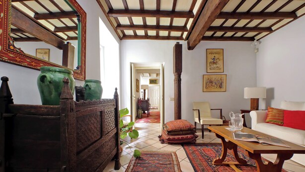 Ein traditionell eingerichtetes Wohnzimmer mit einem Couchtisch aus Holz, einer Couch und einem gemusterten Teppich.