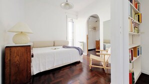 Un dormitorio con cama, un armario de madera, una lámpara, una estantería y una silla.