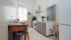 Et lille køkken med spiseplads, med vask, skabe, mikrobølgeovn og køleskab.