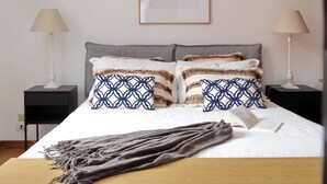 A neatly made bed with patterned pillows, a bedside lamp, and a book on the bed. - Metastasio - One Bedroom Apartment, Sleeps 4 (Rome)