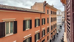 A narrow street with buildings featuring uniform window shutters and a cobblestone road. - Metastasio - One Bedroom Apartment, Sleeps 4 (Rome)