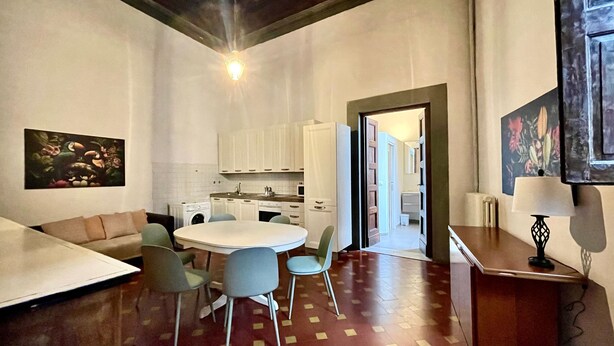 Un espace de vie compact comprenant un coin repas, une kitchenette et un couloir menant à la salle de bain.