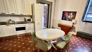 Une cuisine avec des meubles blancs, un four à micro-ondes et une table à manger avec quatre chaises.