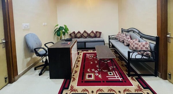 A compact living space with a sofa, a small table, a chair, and a patterned rug. - The Five Dimension Agra (Agra)